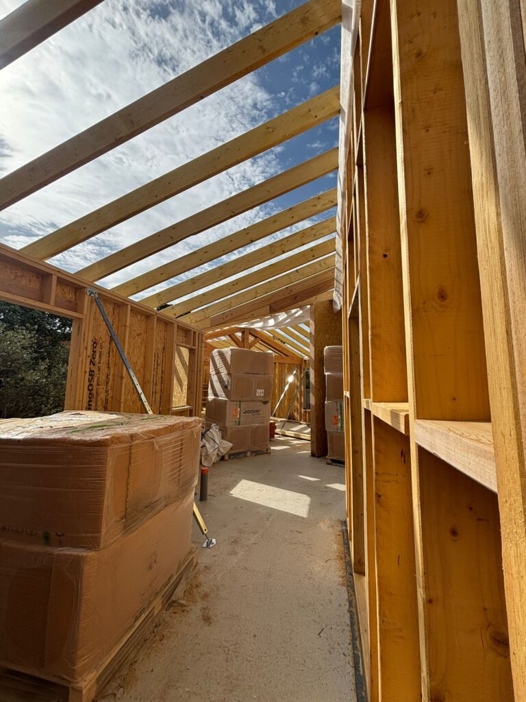 Intérieur de chantier en bois avec charpente apparente, murs en OSB et isolant Isover en attente de pose.